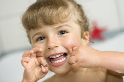 young girl flossing her teeth