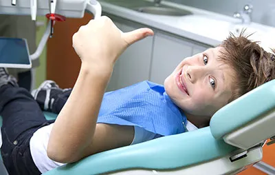 smiling boy giving thumbs up from dental chair